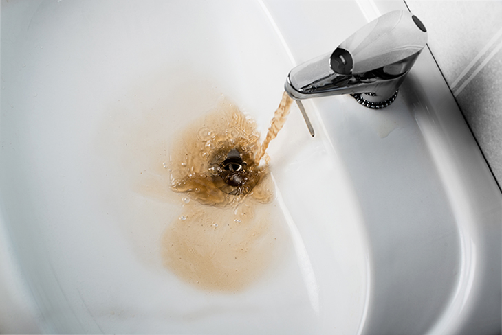 Dirty brown water running into a sink