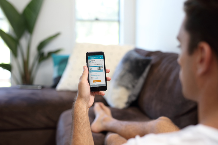 Man looking at mobile phone on couch with account on screen 2