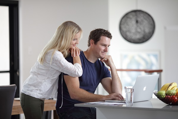 Couple looking at laptop computer on residential kitchen bench