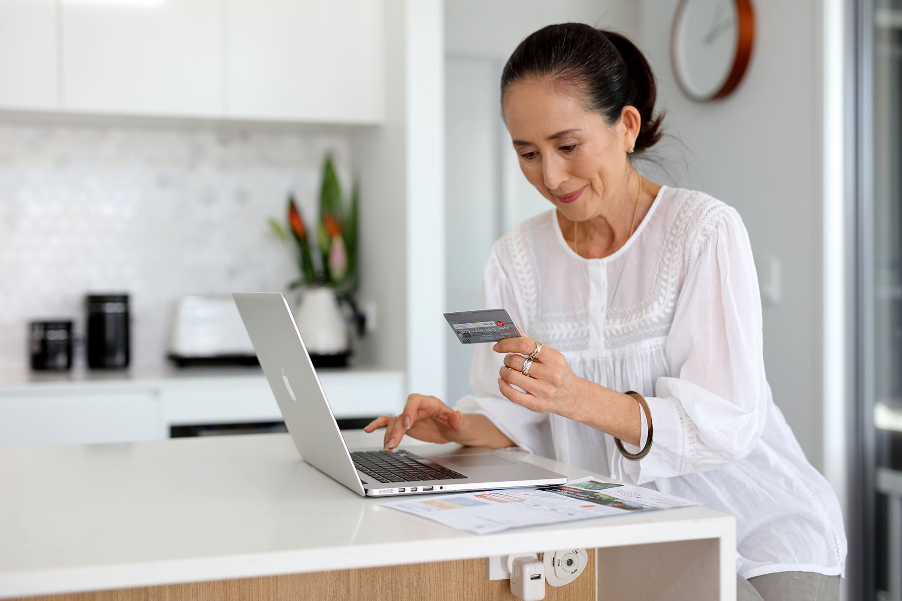 Woman pay bill with credit card on laptop computer in kitchen