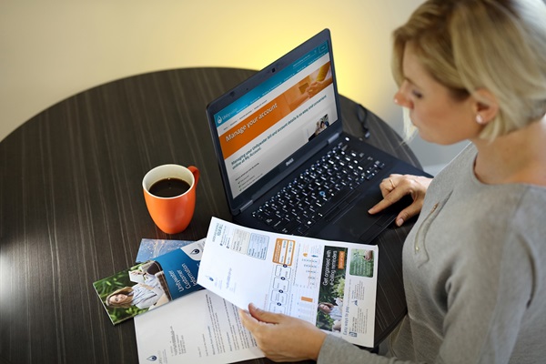 Woman sitting at desk in front of laptop computer looking at Unitywater bill