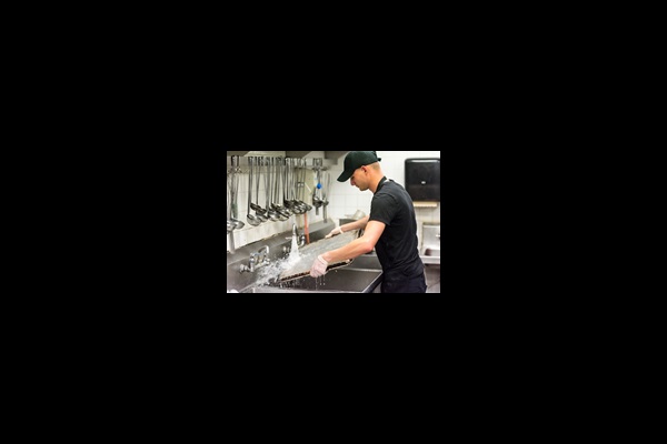 Man washing cooking tray in commercial kitchen