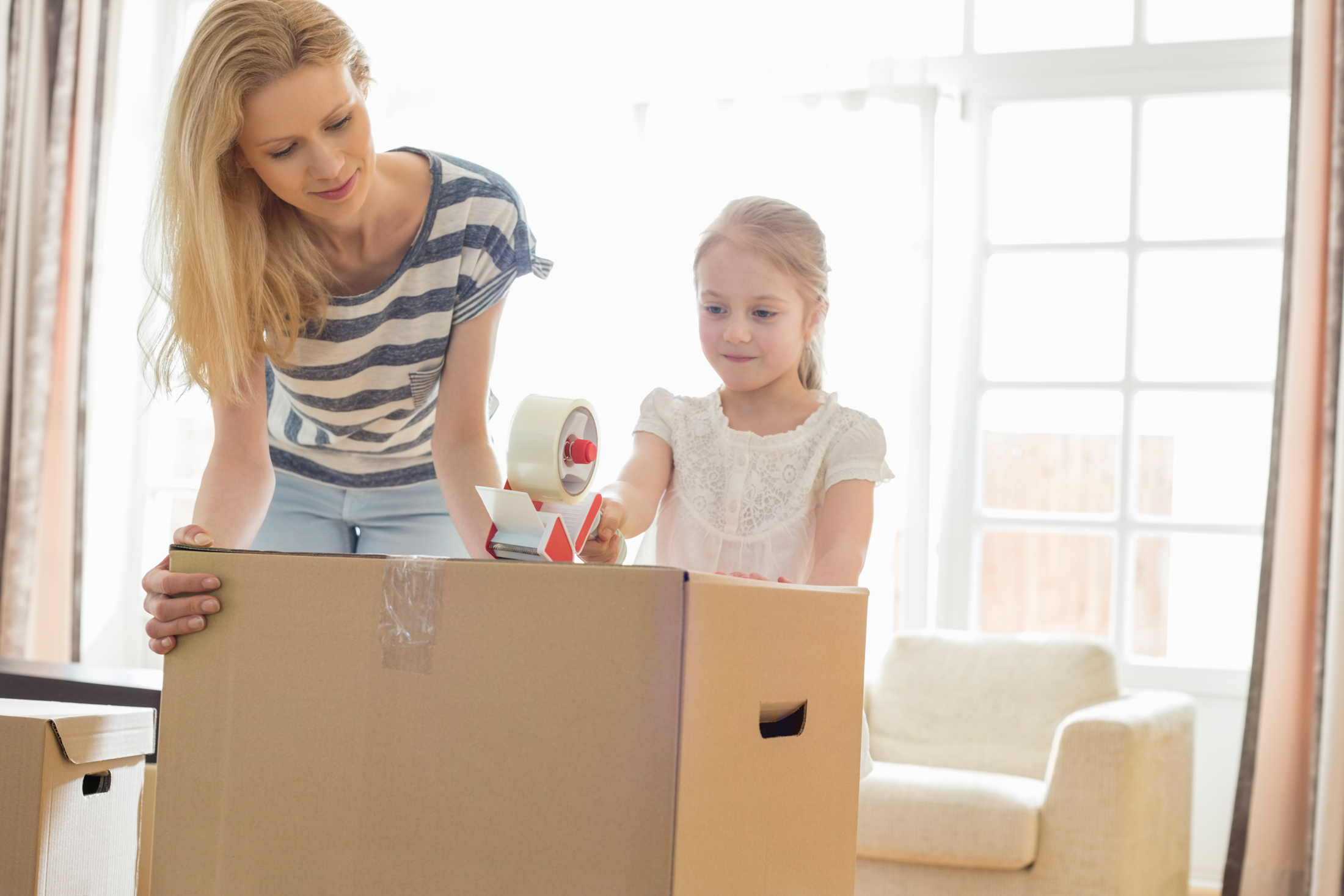 Mother and daughter taping up moving box