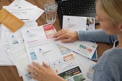 Woman sitting at desk covered in bills and clutter