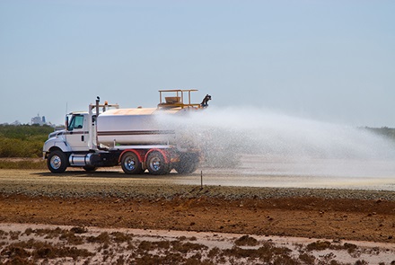 water truck spaying water on road at construction site