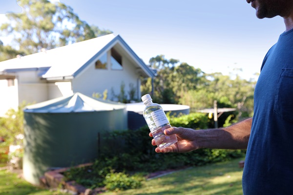 Man collecting water from residential tank for water testing