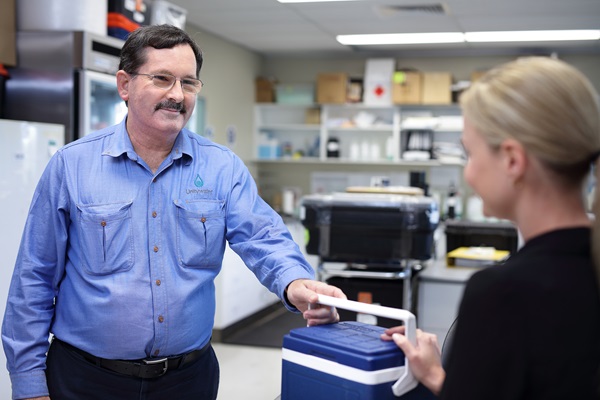 Unitywater lab technician accepting water testing samples in esky from woman