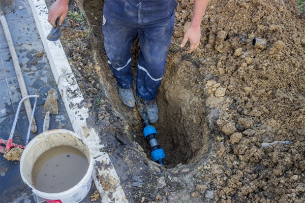 Plumber fixing water leak in pipe under ground