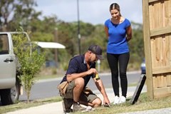 Plumber and woman looking into water meter box in front of residential house