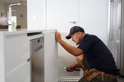 Plumber repairing leak in kitchen