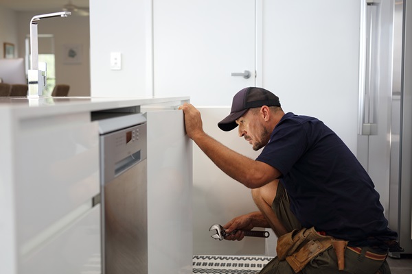 Plumber repairing leak in kitchen