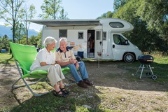 Senior couple camping with camper van