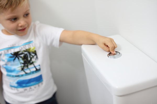 Young boy flushing toilet in bathroom of residential house