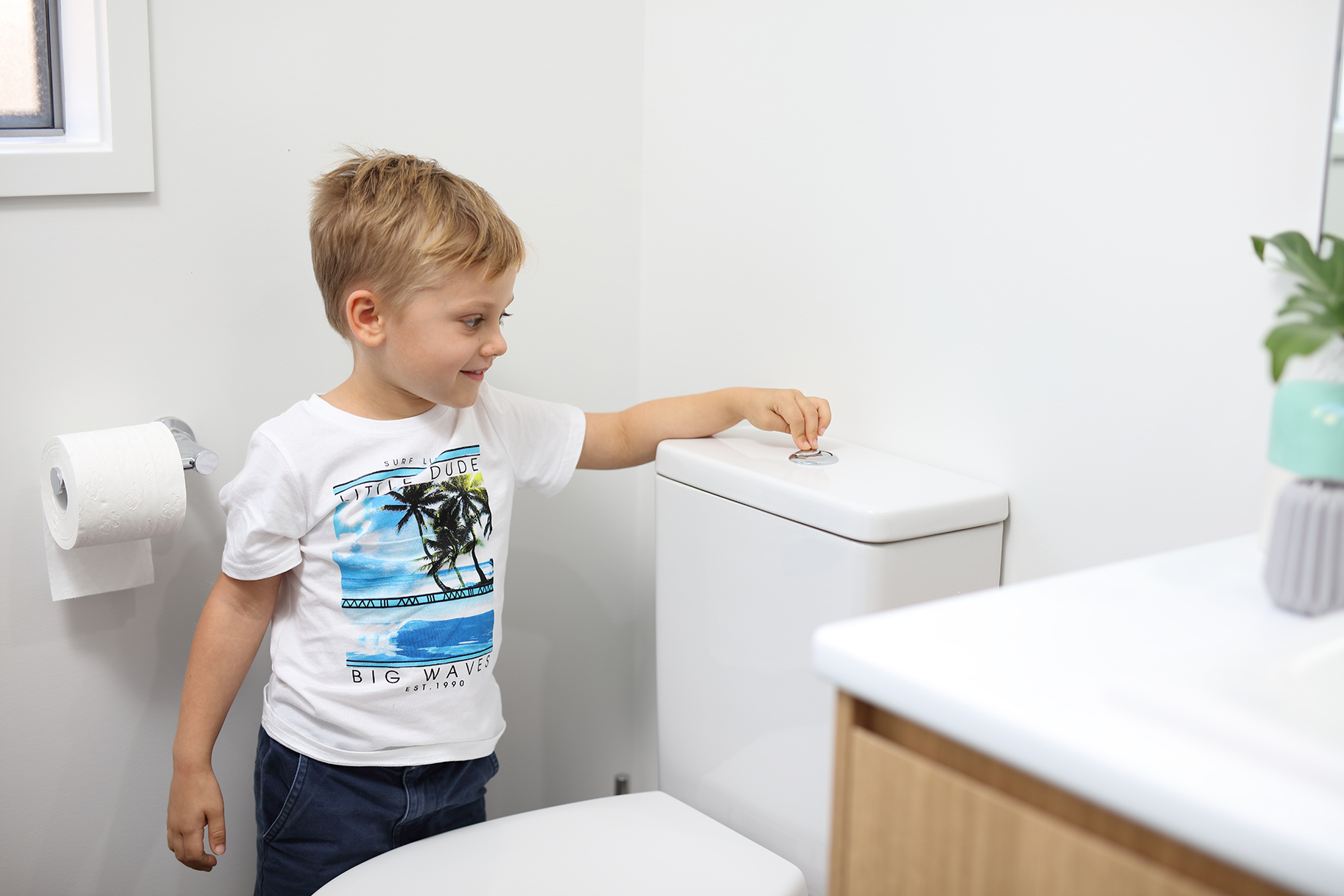 Young boy flushing toilet in bathroom of residential house