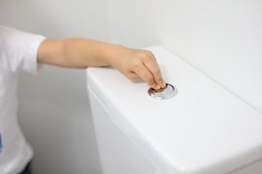 Young boy flushing toilet in bathroom of residential house