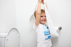 Young boy playing with toilet paper in bathroom of residential house