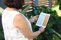 Woman looking at Unitywater Tree Planting Guide in residential garden