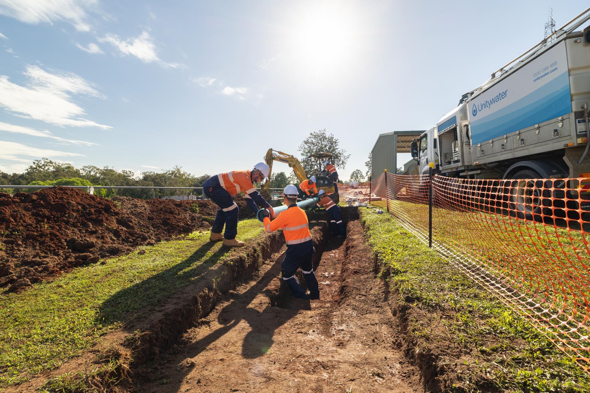 Unitywater field crew placing new water main pipe in ground