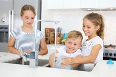 Children filling water bottles at kitchen sink
