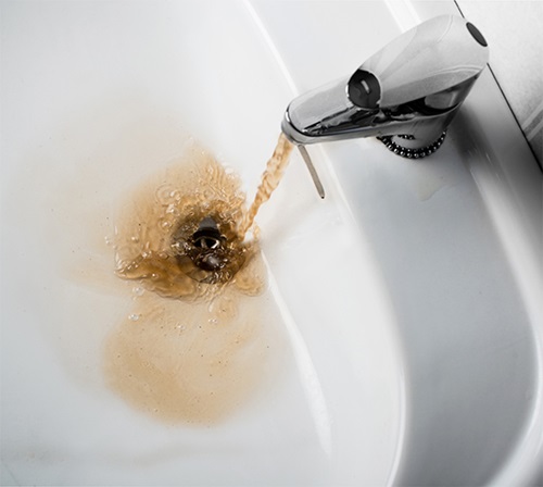 Dirty brown water running into a sink