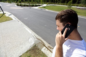 Man calling on mobile phone to report a water leak on street