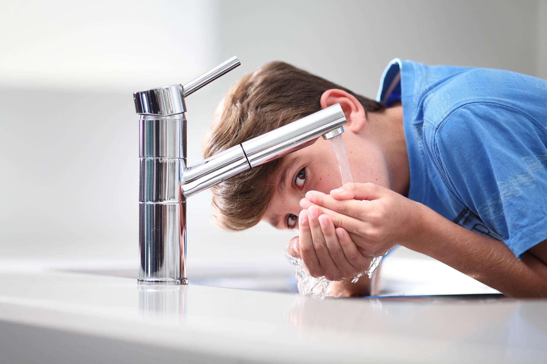 Boy drinking from bathroom tap