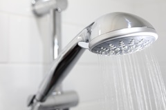 Shower head spraying water in residential bathroom