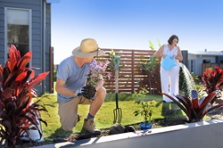 Man planting flowers and woman watering garden in residential garden