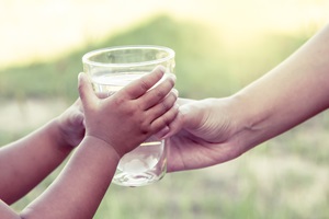 Woman handing child a glass of water